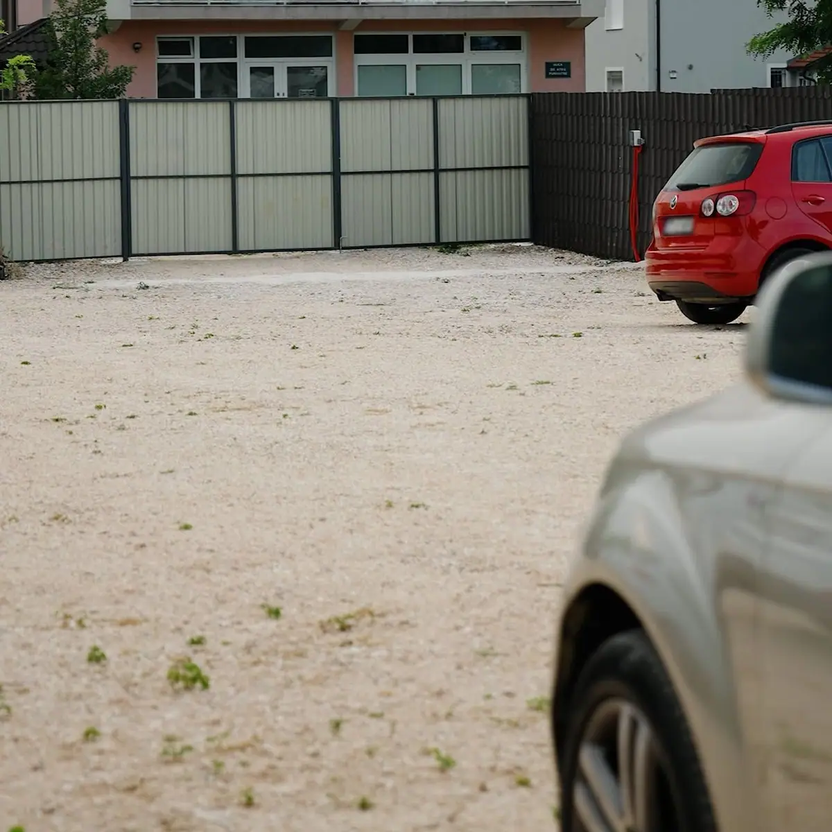 Prostran šljunčani parking s ogradom i kapijom