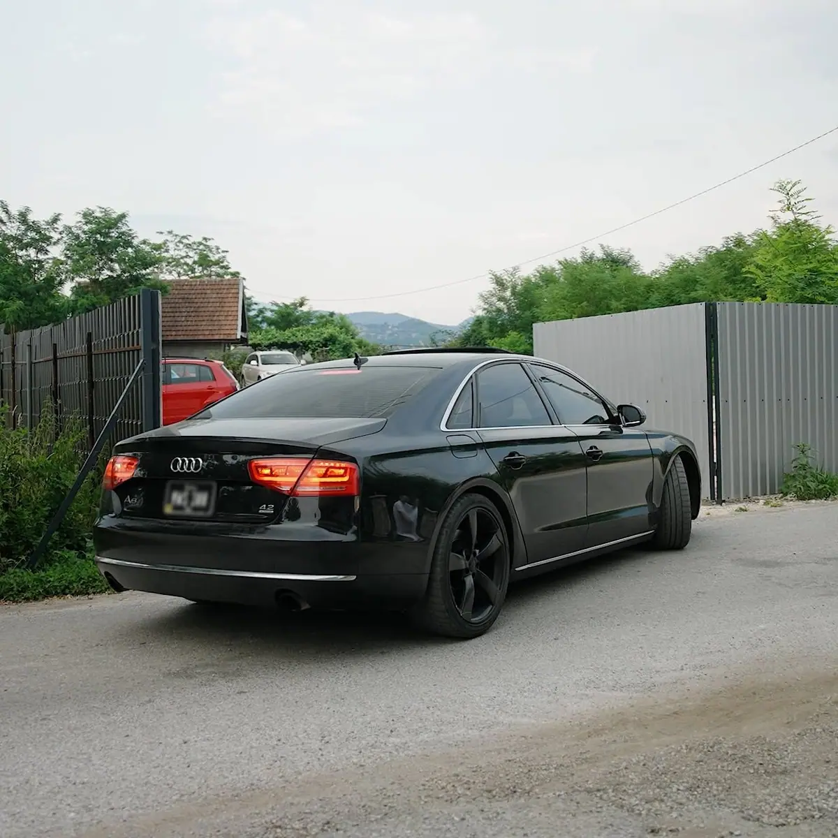 Crni automobil ulazi na parking kroz limenu kapiju