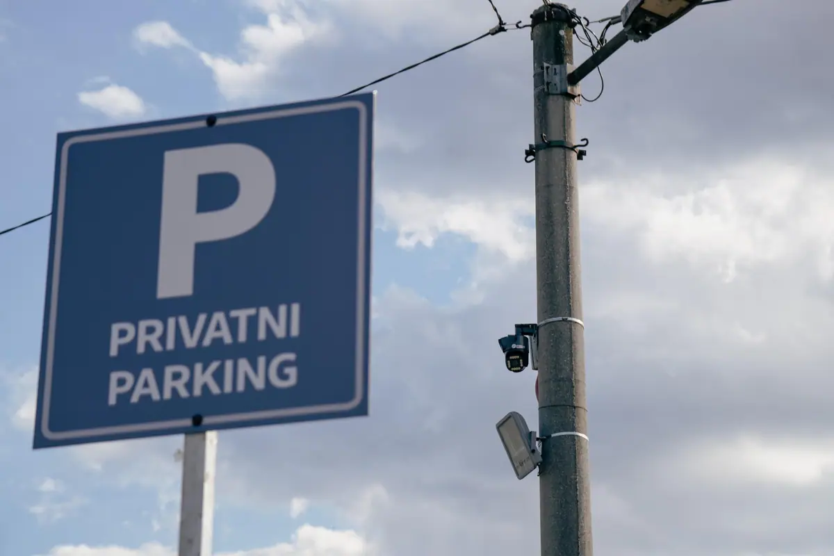 Plava oznaka Privatni parking i stub s video nadzornom kamerom i reflektorom